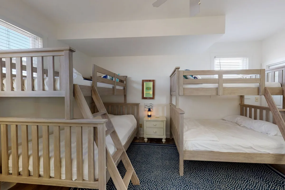 A cheerful bunk room featuring sturdy bunk beds, a nightstand with a lamp, and a decorative mirror. The playful layout and cozy atmosphere make it an inviting space for children to play, share stories, and create memories.