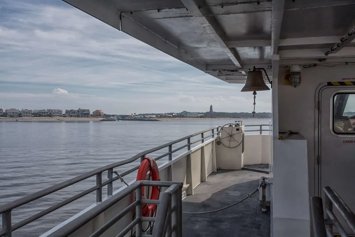 A view from the ferry deck, complete with a life ring in the foreground and the island’s shoreline visible in the distance. The tranquil water and open sky set a serene tone, capturing the start of the Bald Head Island adventure.